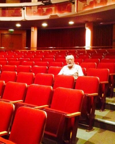 Marvin Carlson sitting in a seat alone in the orchestra section of the Kiplinger Theatre.